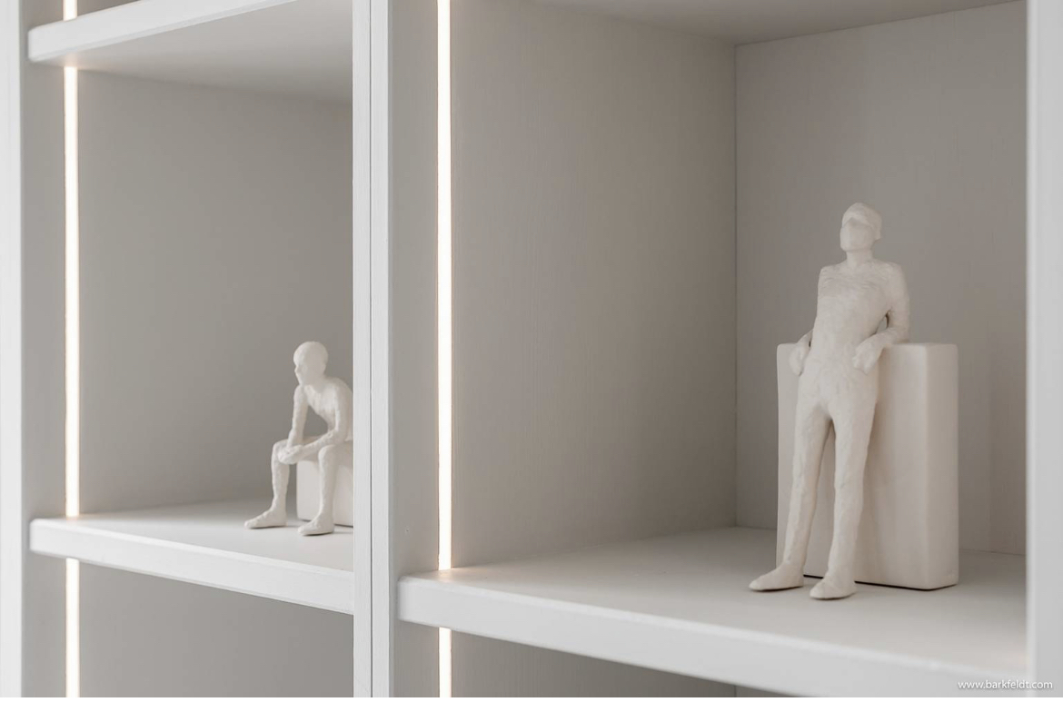 Närbild specialsnickerier av en vit platsbyggd bokhylla med belysning
