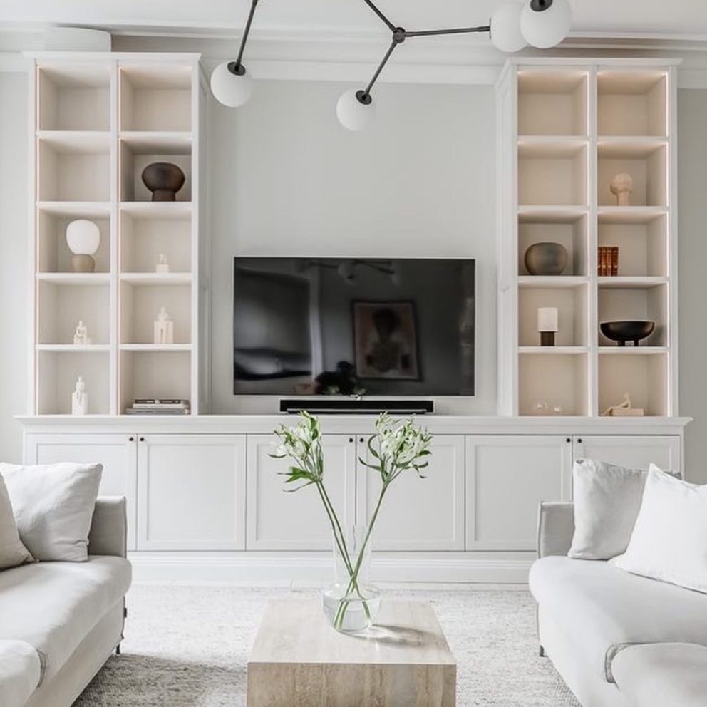 Ljust vardagsrum med vit platsbyggd bokhylla med tv