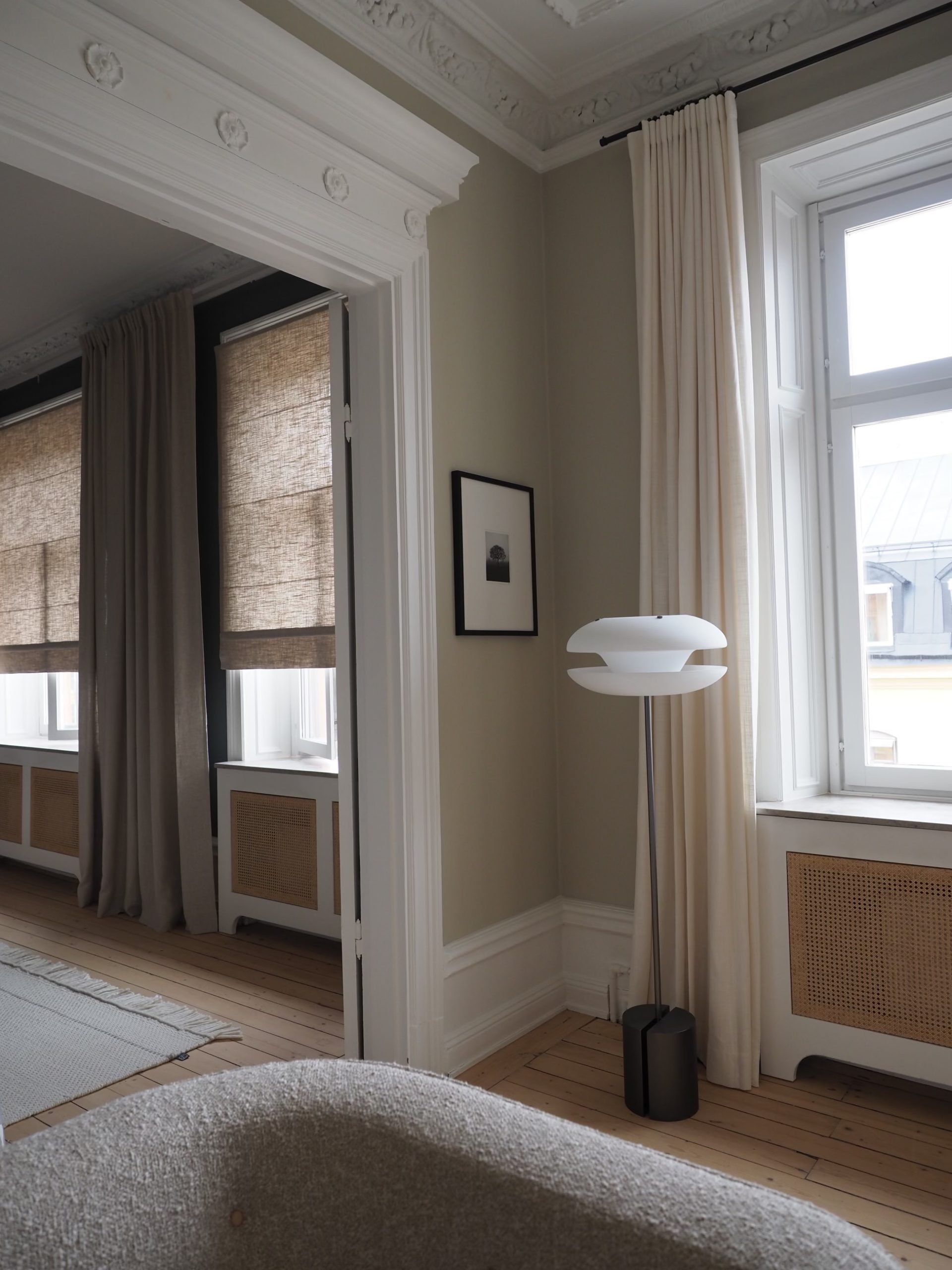 Sekelskiftes lägenhet med beiga tapeter och vita elementskydd med rotting
